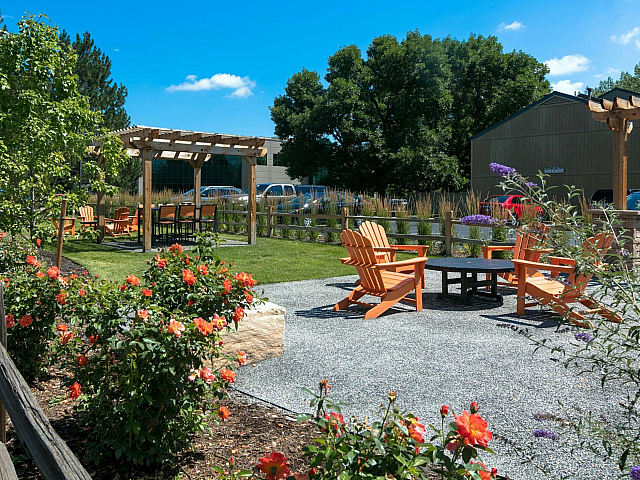 Inviting outdoor garden space featuring vibrant flowers, comfortable seating, and a picturesque pergola under a clear blue sky.