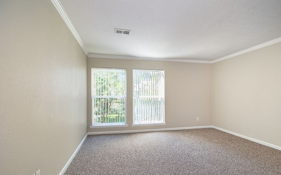 Bright and inviting empty room with plush carpet and large windows letting in natural light.