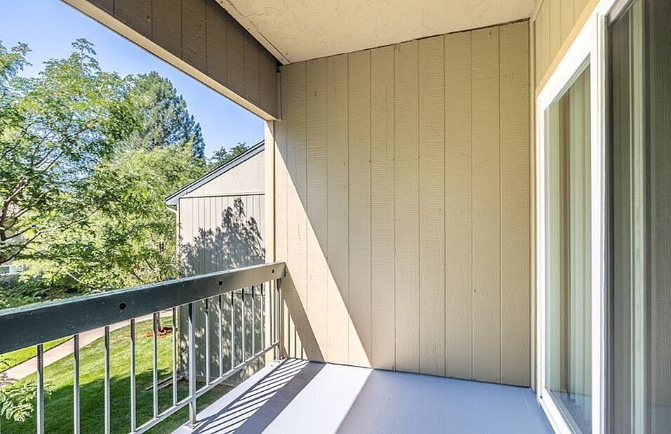 Bright balcony with wooden railing, overlooking lush greenery, perfect for peaceful relaxation.