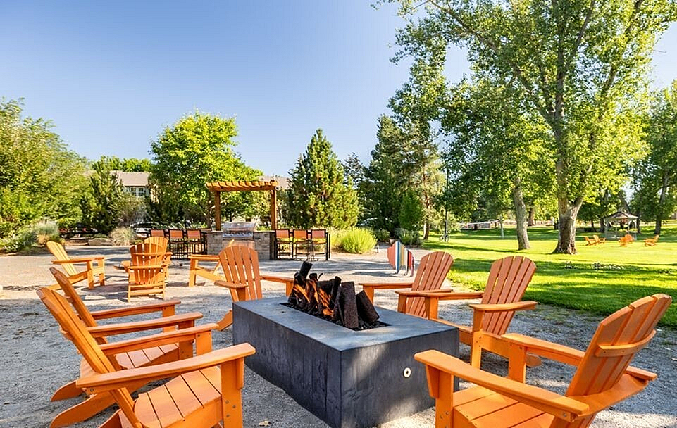 Inviting outdoor space with vibrant orange chairs surrounding a cozy fire pit, nestled in a lush green setting perfect for relaxation.