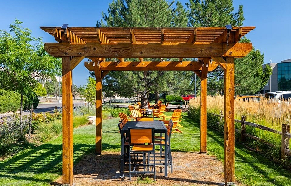 Charming outdoor patio with a wooden pergola, cozy seating, and lush green surroundings, perfect for relaxing gatherings.