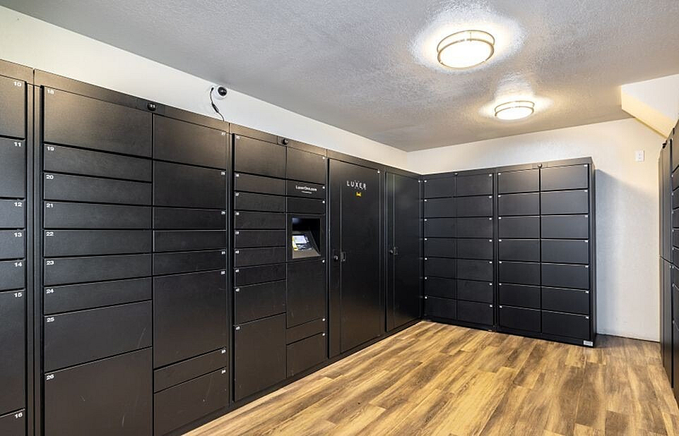 Modern apartment mailroom featuring sleek black parcel lockers with convenient package retrieval system and ambient lighting.