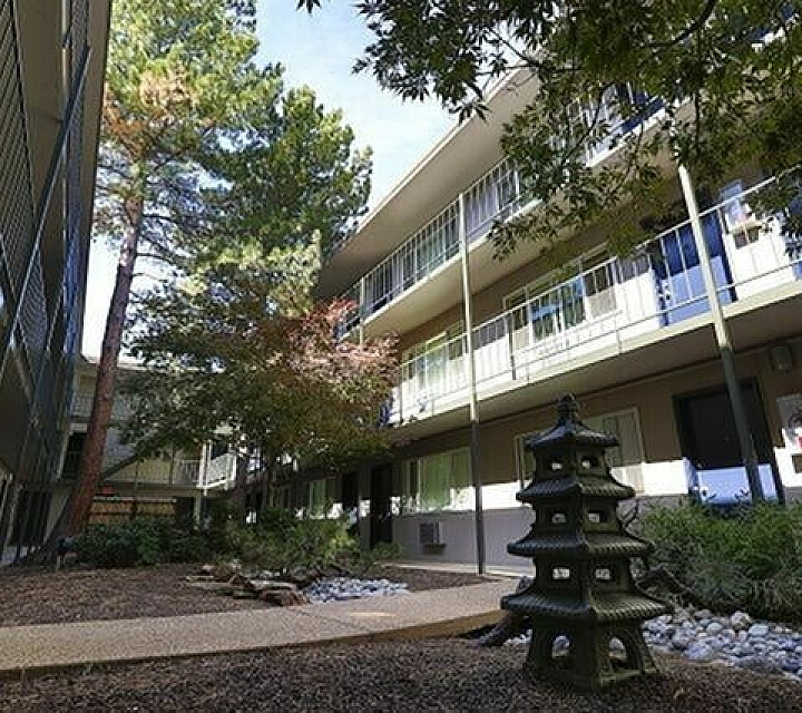 Charming apartment courtyard featuring lush greenery, a tranquil garden path, and contemporary architecture with stylish balconies.