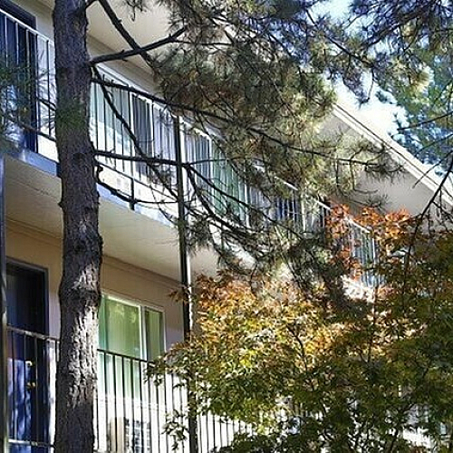 Charming apartment exterior with private balconies and lush greenery, highlighting a tranquil living environment.