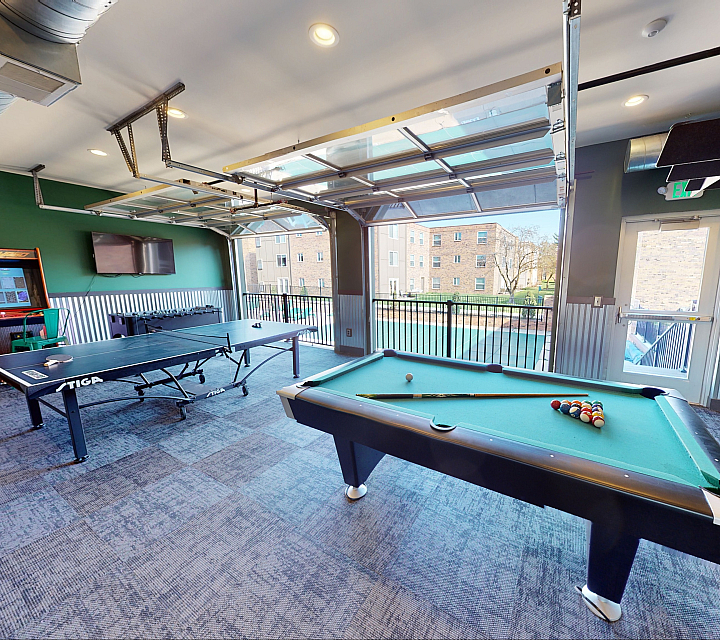 Vibrant recreation room featuring a stylish pool table, modern ping pong setup, and large windows with outdoor views.