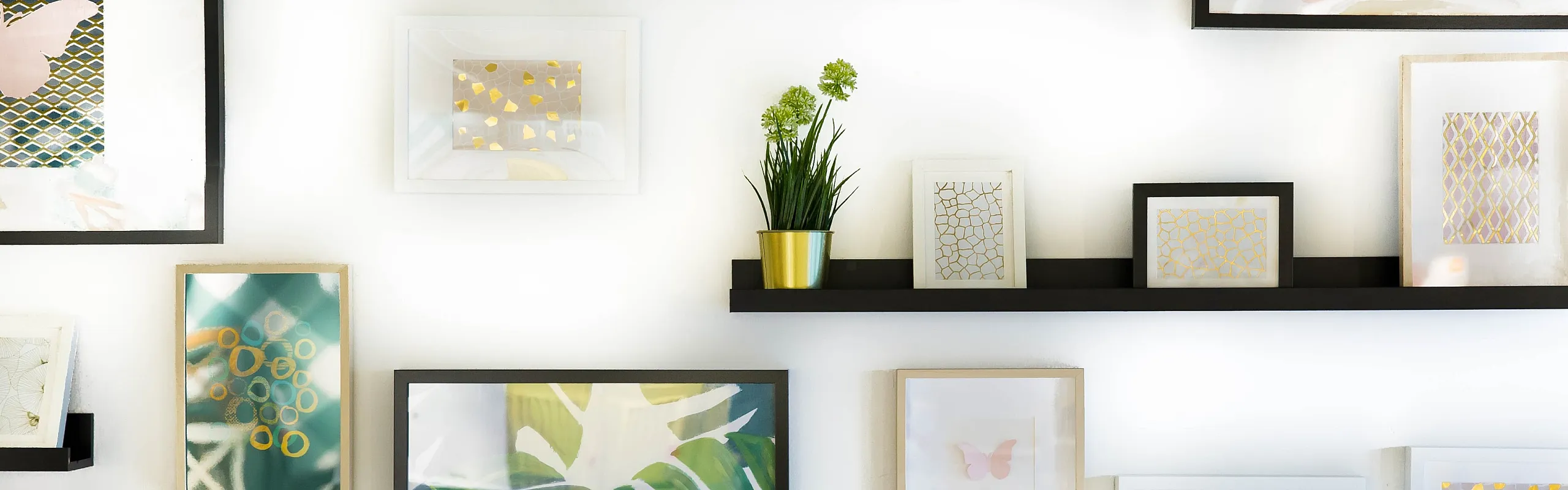 Gallery wall with colorful framed artwork, decorative prints, and small potted plants.