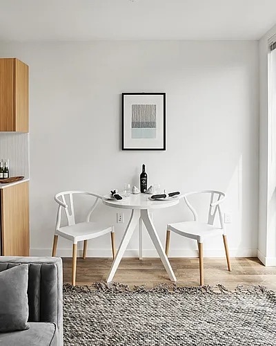 Bright, modern apartment interior with cozy living area, compact kitchen, and dining table by large windows with city views