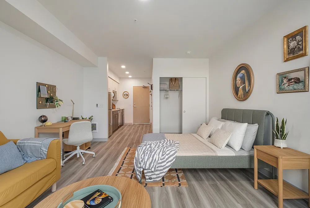 Spacious studio apartment at The Nook at Northaven featuring bed, desk, and modern kitchen.