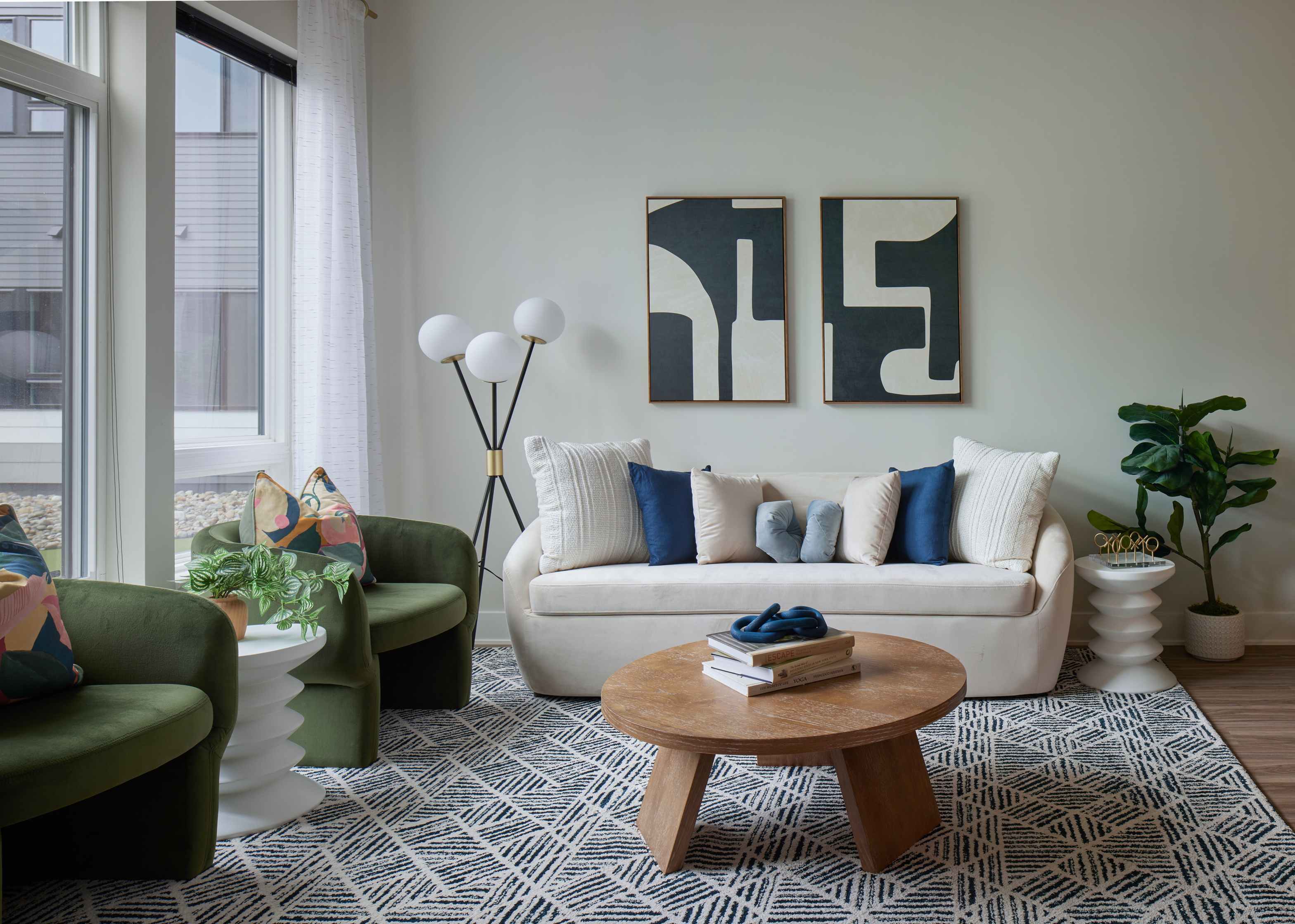Montgomeryville apartment iving room with a white sofa, green chairs, abstract wall art, and a wooden coffee table.