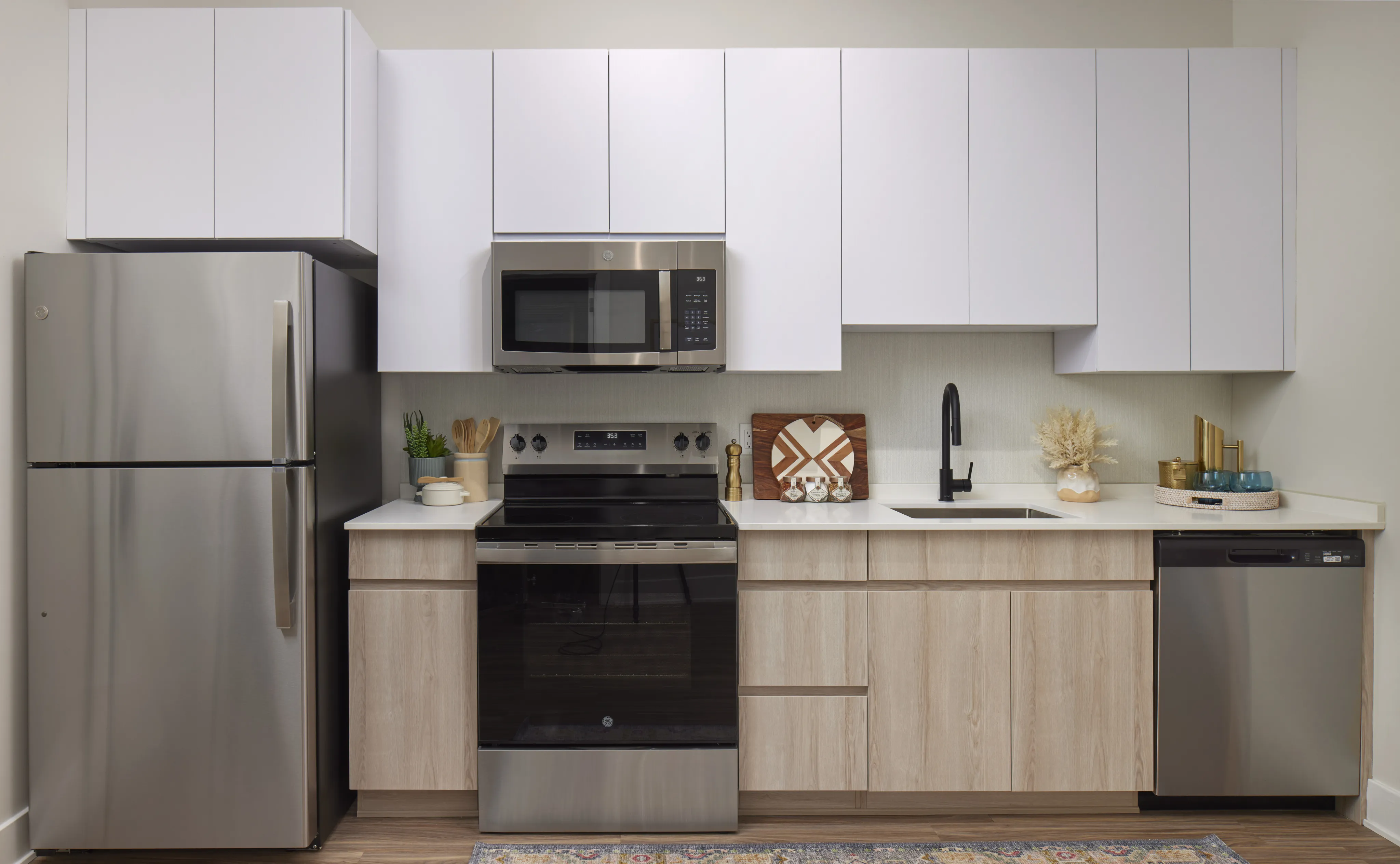 Sleek kitchen with white cabinets, stainless steel appliances, wood accents, and minimalist decor.