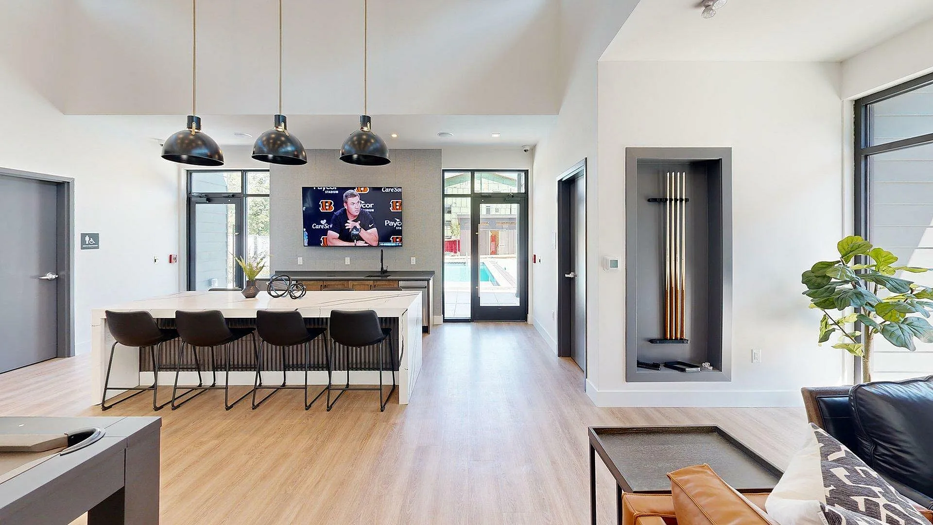 Chic open-concept lounge area with modern lighting, sleek bar seating, and a pool view, ideal for entertaining.