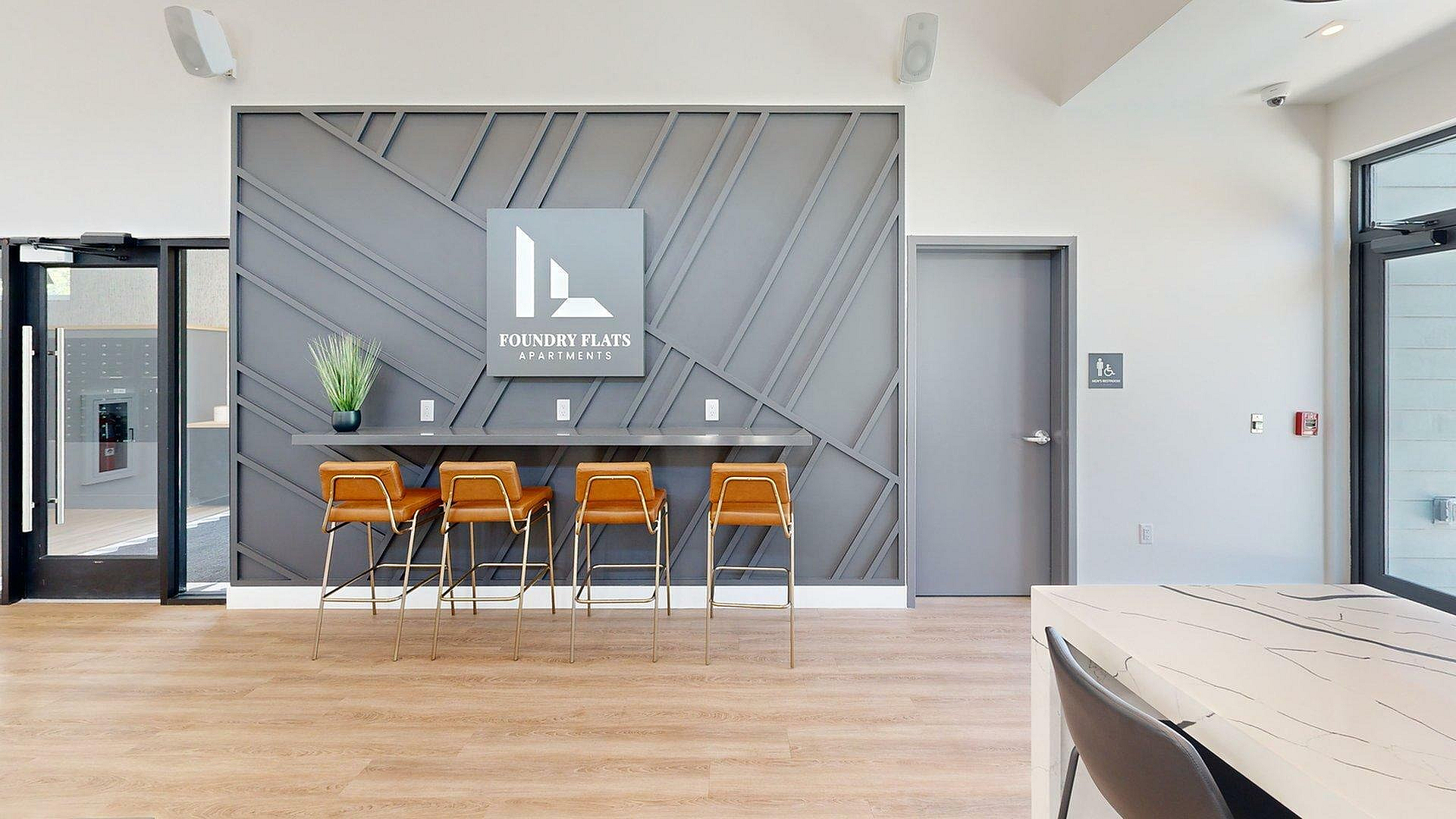 Modern lobby of Foundry Flats Apartments featuring stylish seating and a geometric wall design.