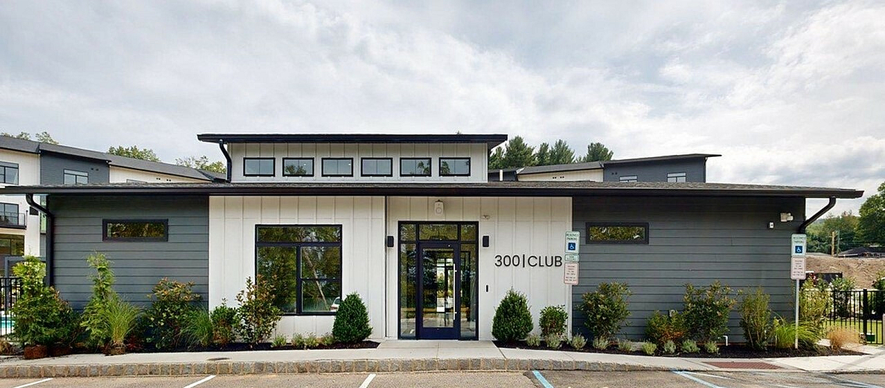 Chic apartment complex entrance with modern design, large windows, and lush landscaping, inviting you to a sophisticated lifestyle at 300 Club.