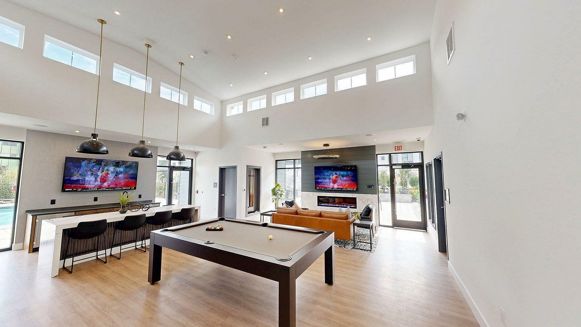 Modern apartment lounge with high ceilings, stylish billiards table, cozy seating area, and a sleek bar perfect for entertaining.