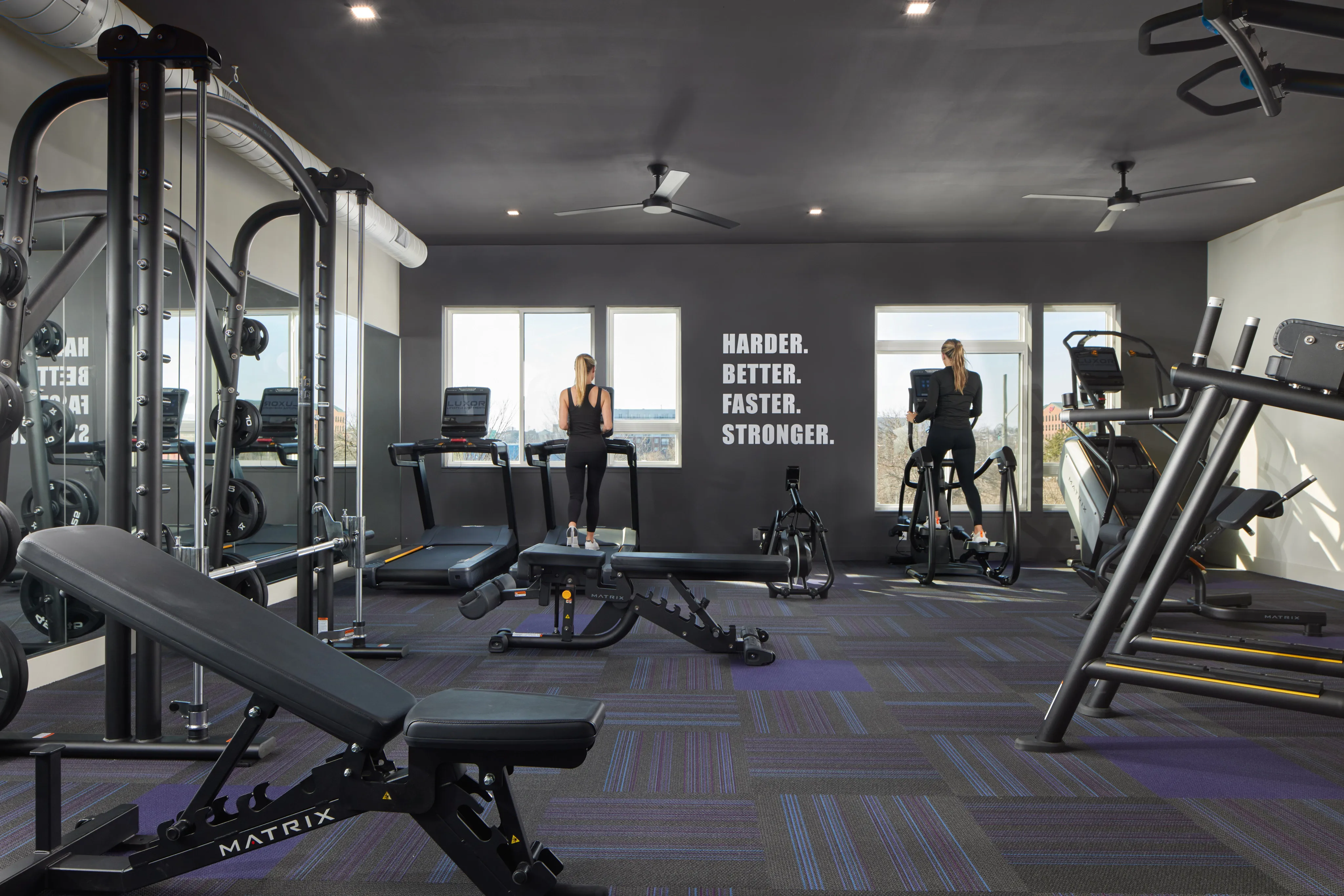 Modern fitness center with state-of-the-art equipment, vibrant flooring, and motivational wall decor.