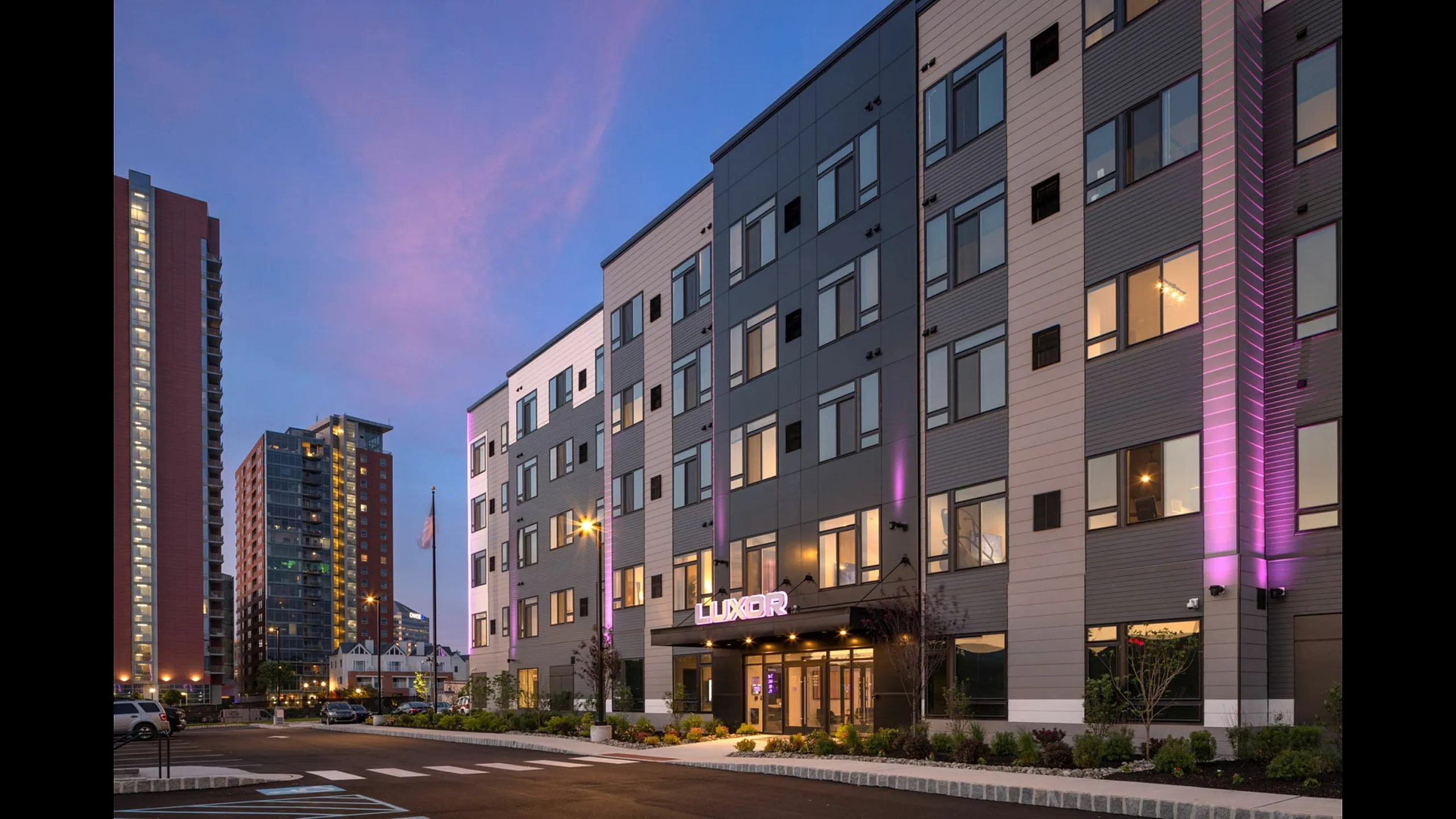 Modern apartment building exterior with elegant lighting and contemporary design at dusk.