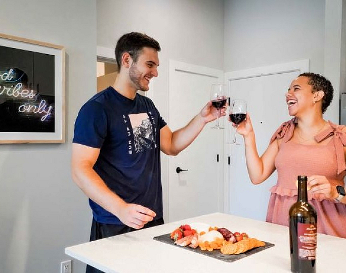 Charming and modern kitchen space featuring a couple enjoying wine and appetizers beneath a cheerful 'good vibes only' sign.