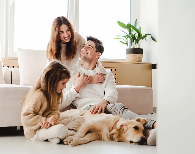 Happy family enjoying quality time in a bright and cozy living space with a golden retriever, showcasing a welcoming and pet-friendly atmosphere.