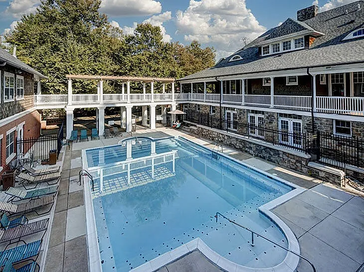 Luxurious outdoor pool area surrounded by elegant architecture and lush greenery, featuring comfortable lounge chairs.
