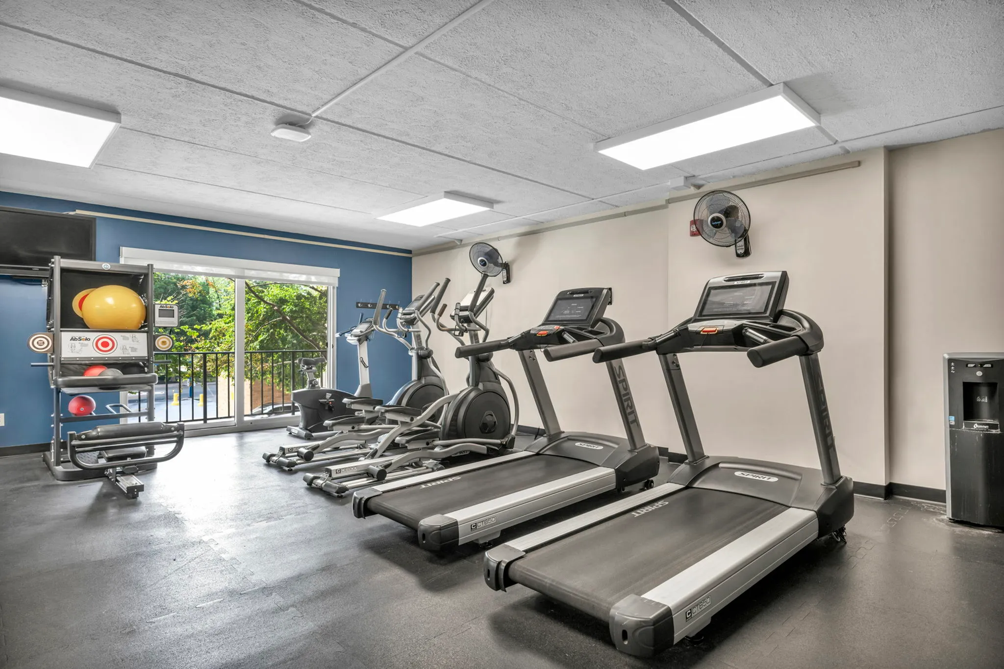 Modern apartment gym with state-of-the-art cardio equipment, including treadmills and ellipticals, vibrant exercise balls, and an inviting view.