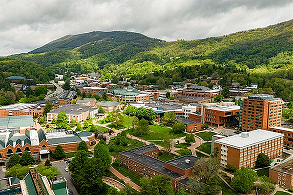 Stunning aerial view of a vibrant town nestled among lush green mountains, showcasing a blend of modern architecture and natural beauty.