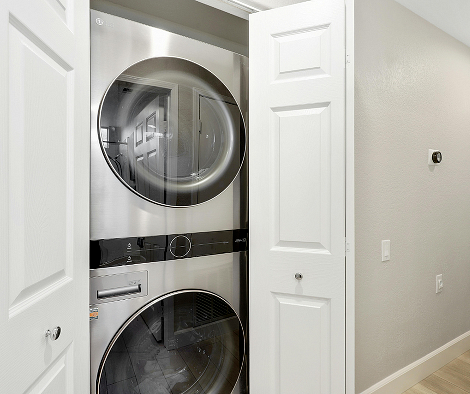 Modern stacked washer and dryer set in a sleek, spacious closet with polished white doors, perfect for efficient and stylish in-home laundry.