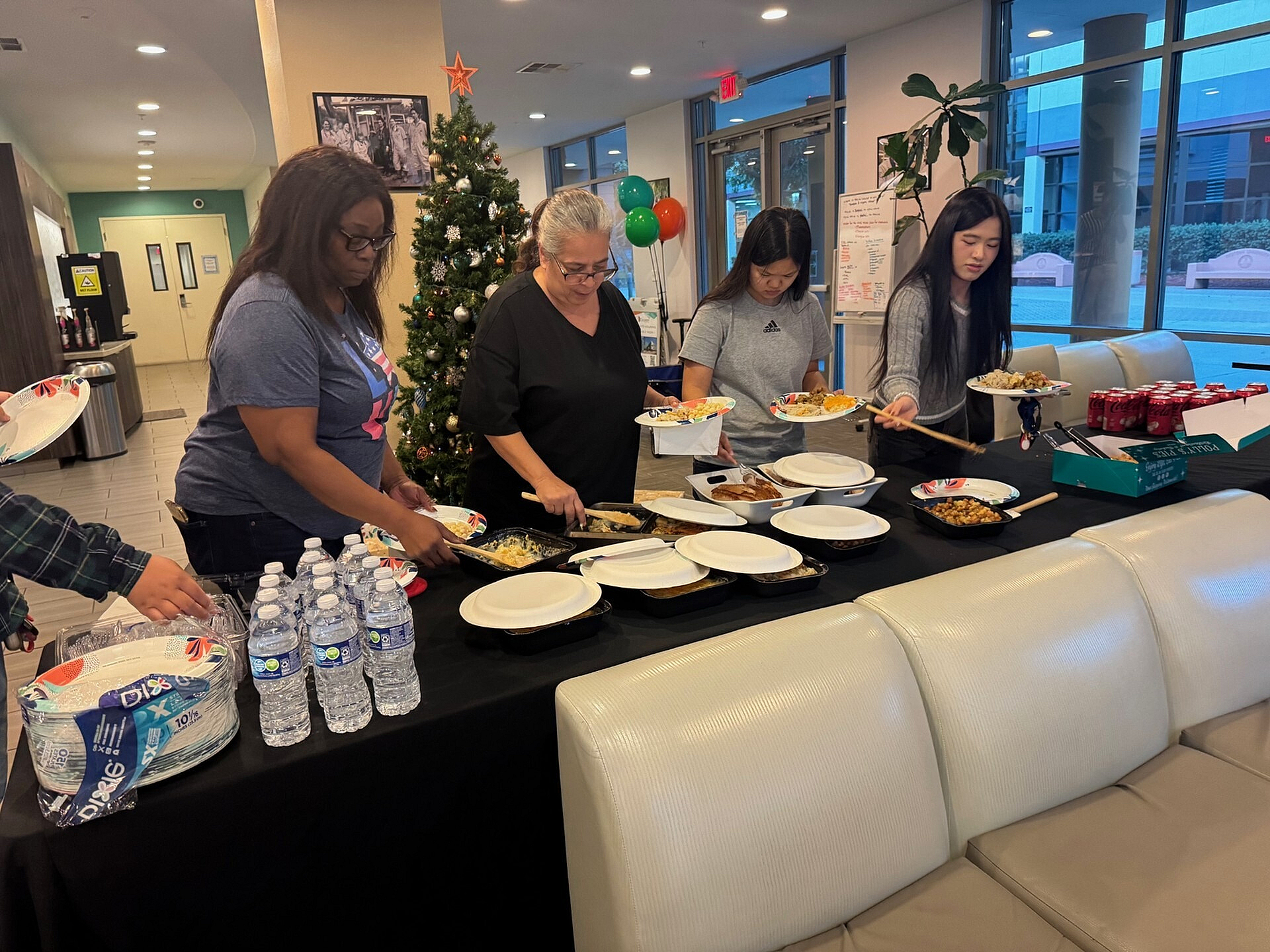 Festive holiday gathering with people enjoying a delicious buffet in a cozy, decorated room with a Christmas tree.