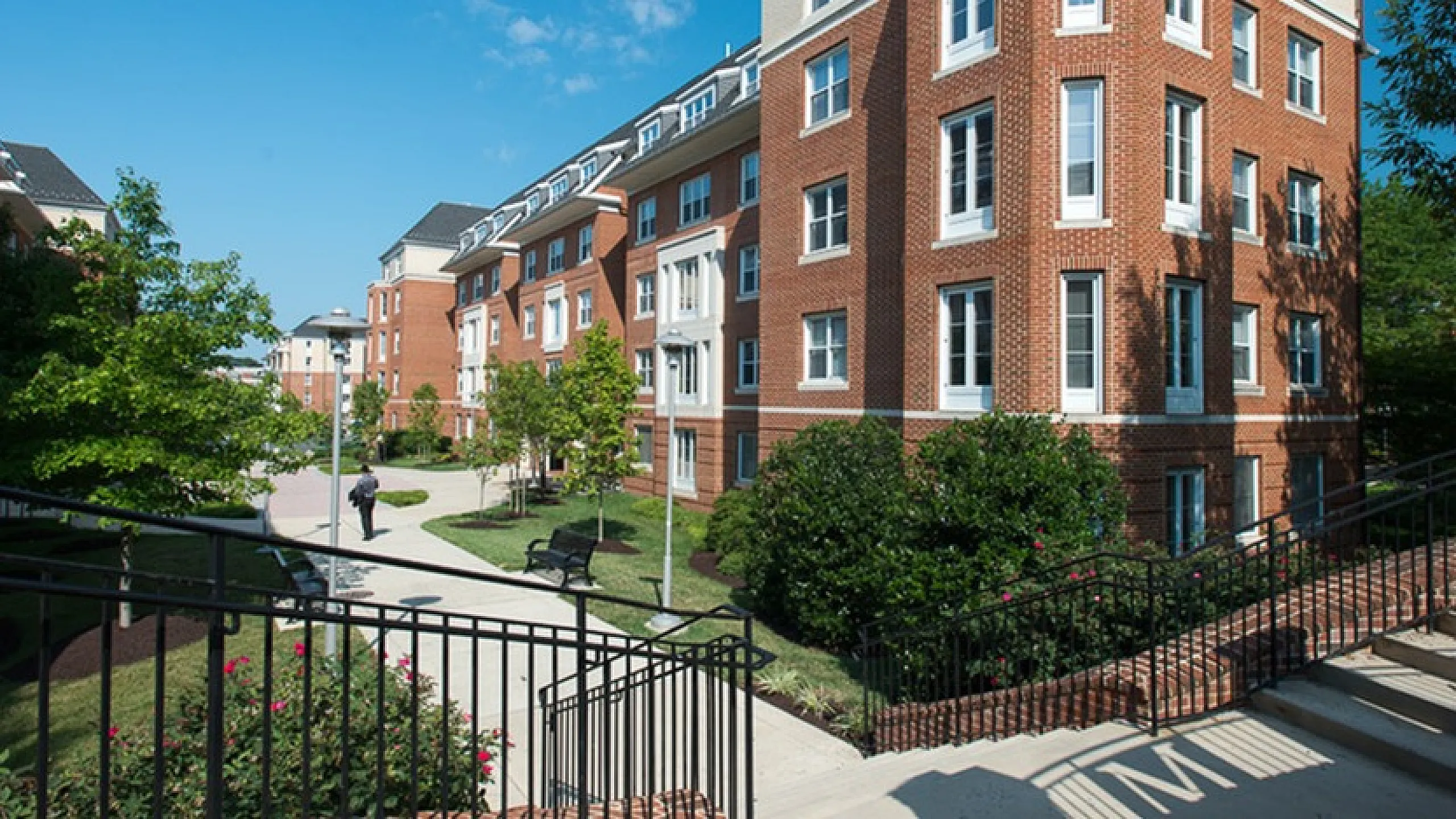 Elegant brick apartment building with lush landscaping and clear blue skies.