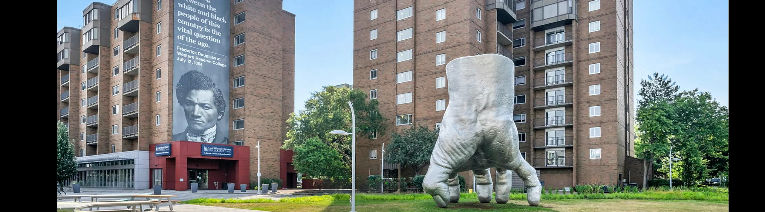 Contemporary apartment building with unique sculpture and mural in a vibrant urban setting.