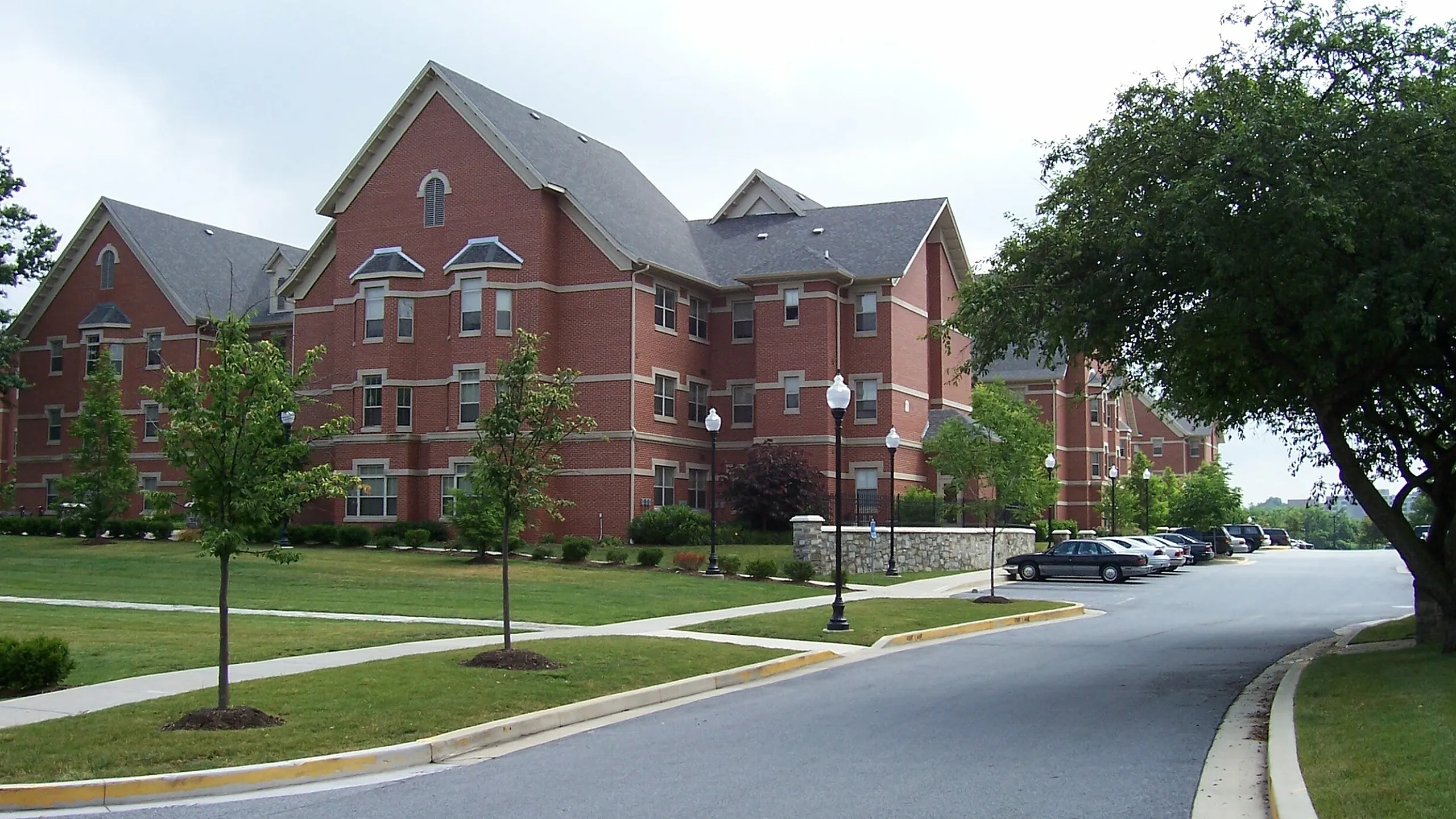 Picturesque brick apartment complex with lush green surroundings and ample parking.