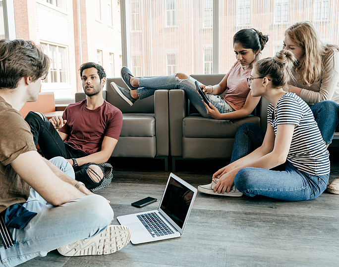 Bright and modern communal living space with young adults engaging in lively discussion, highlighting a comfortable and inviting apartment setting.