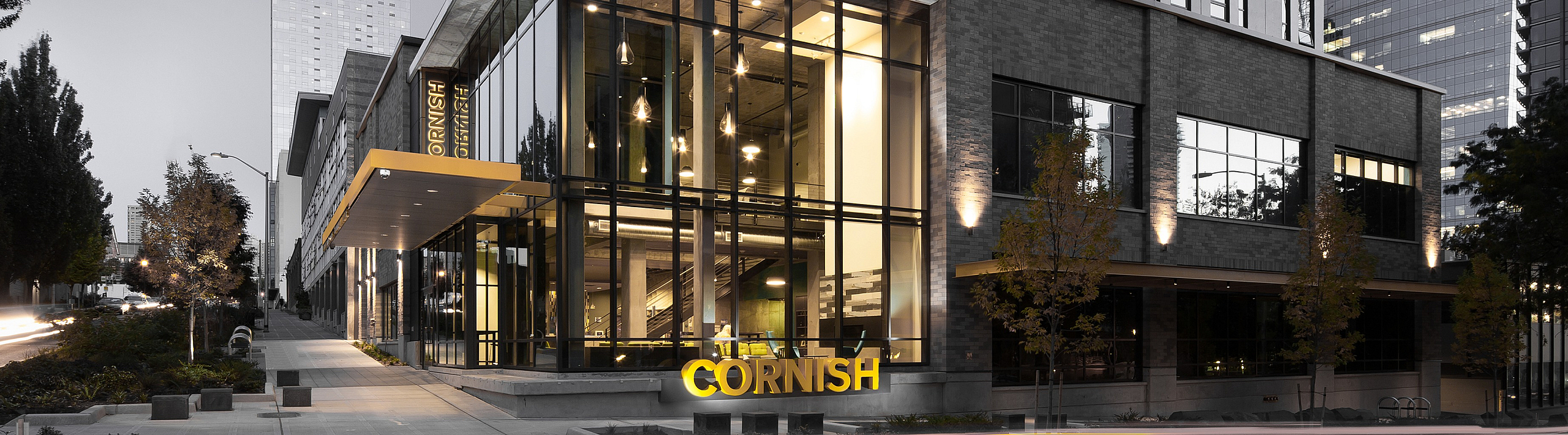 Modern urban apartment building with sleek glass facade, featuring bright interior lighting and dynamic city surroundings.