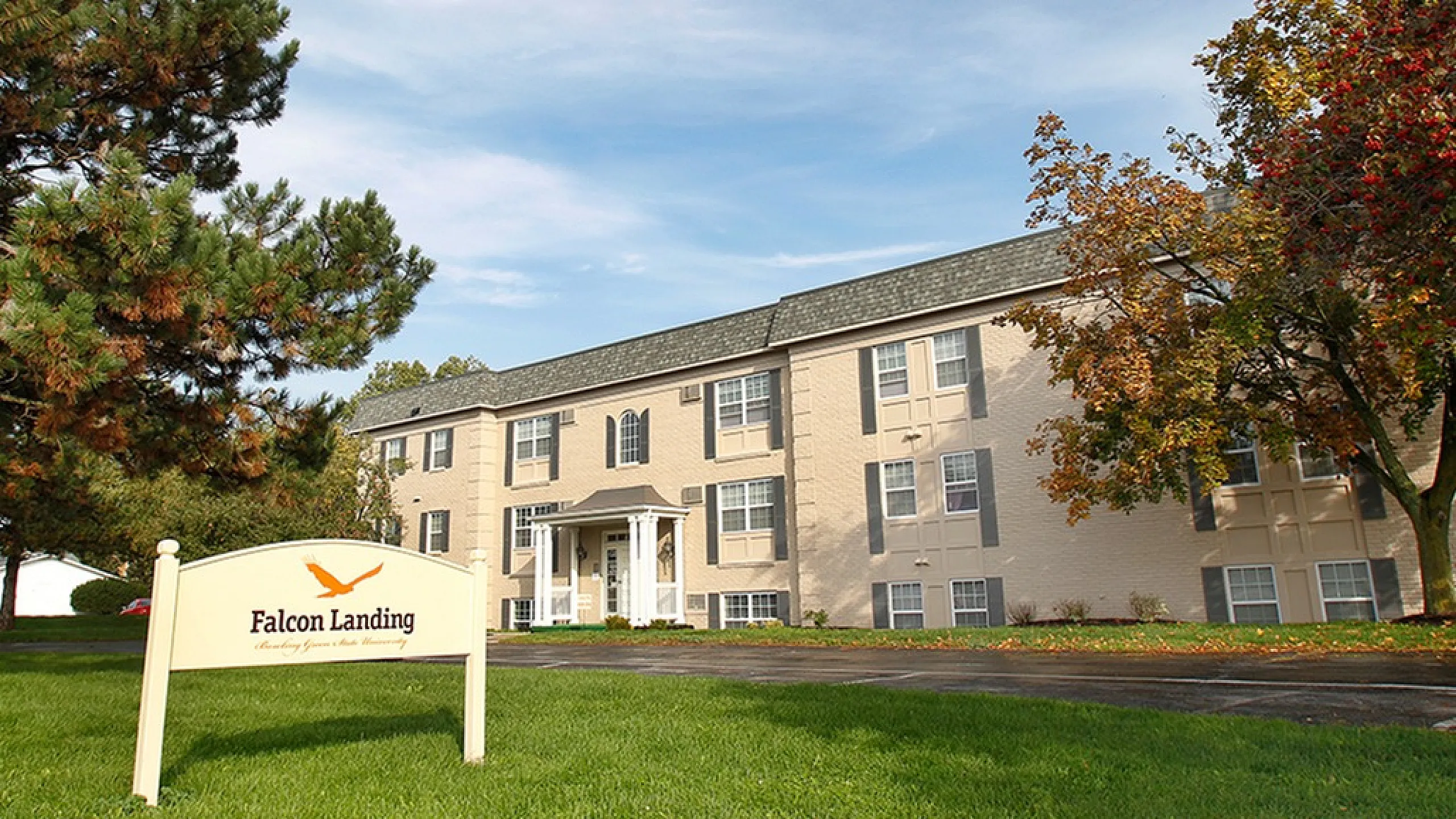 Charming Falcon Landing apartment complex surrounded by lush greenery and bright skies, offering serene living.