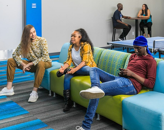 Vibrant community space with modern seating, a ping pong table, and groups of people enjoying socializing, perfect for residents looking for a lively environment.