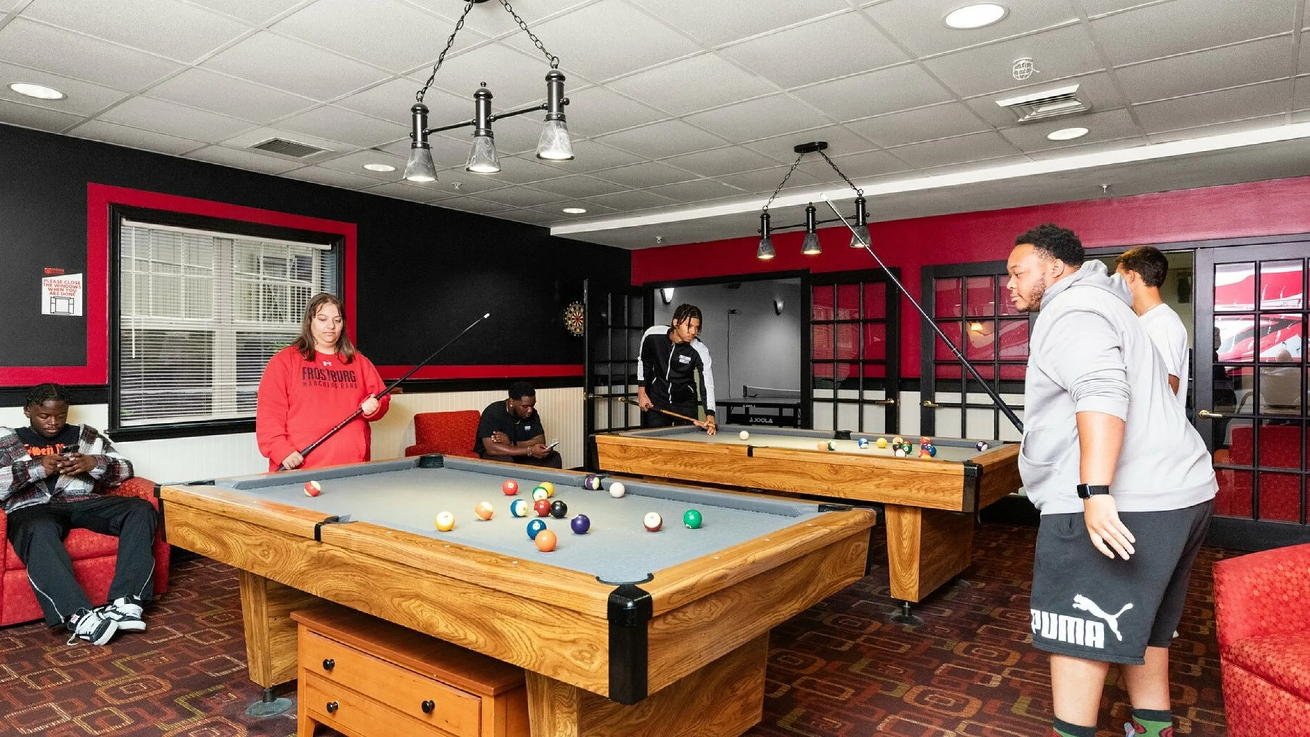 Vibrant communal game room with two pool tables and stylish decor, offering a perfect space for social gatherings and entertainment.