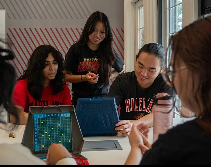 Group of young adults enjoying a strategy board game, fostering camaraderie and teamwork in a bright, modern setting.