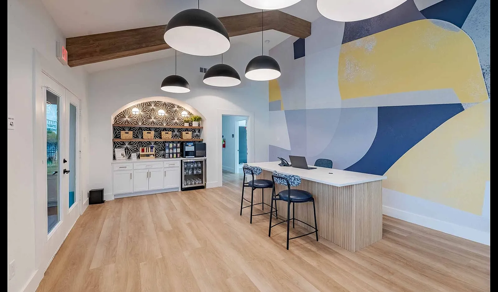 Modern communal space with sleek bar seating, stylish pendant lights, and vibrant geometric wall art.