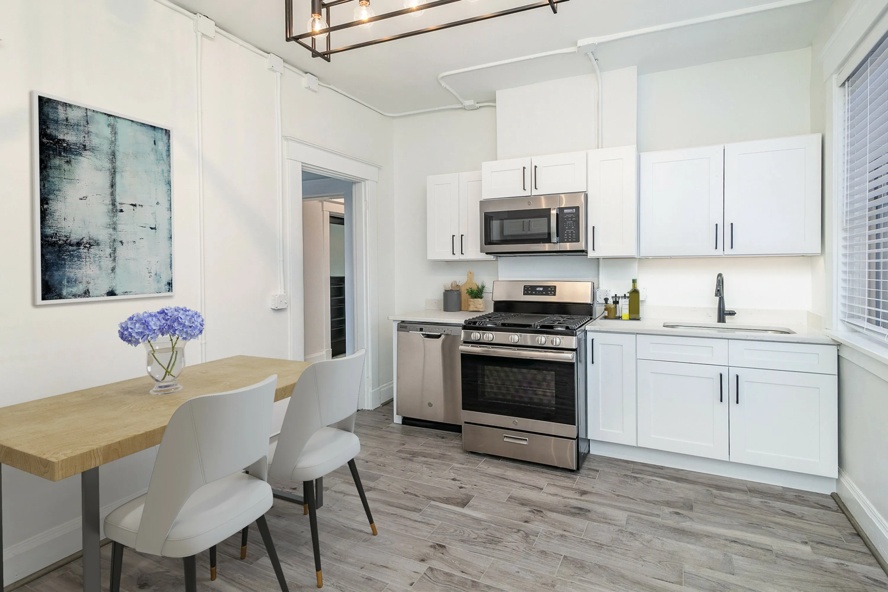 Modern kitchen with sleek white cabinets, stainless steel appliances, and a stylish dining area.