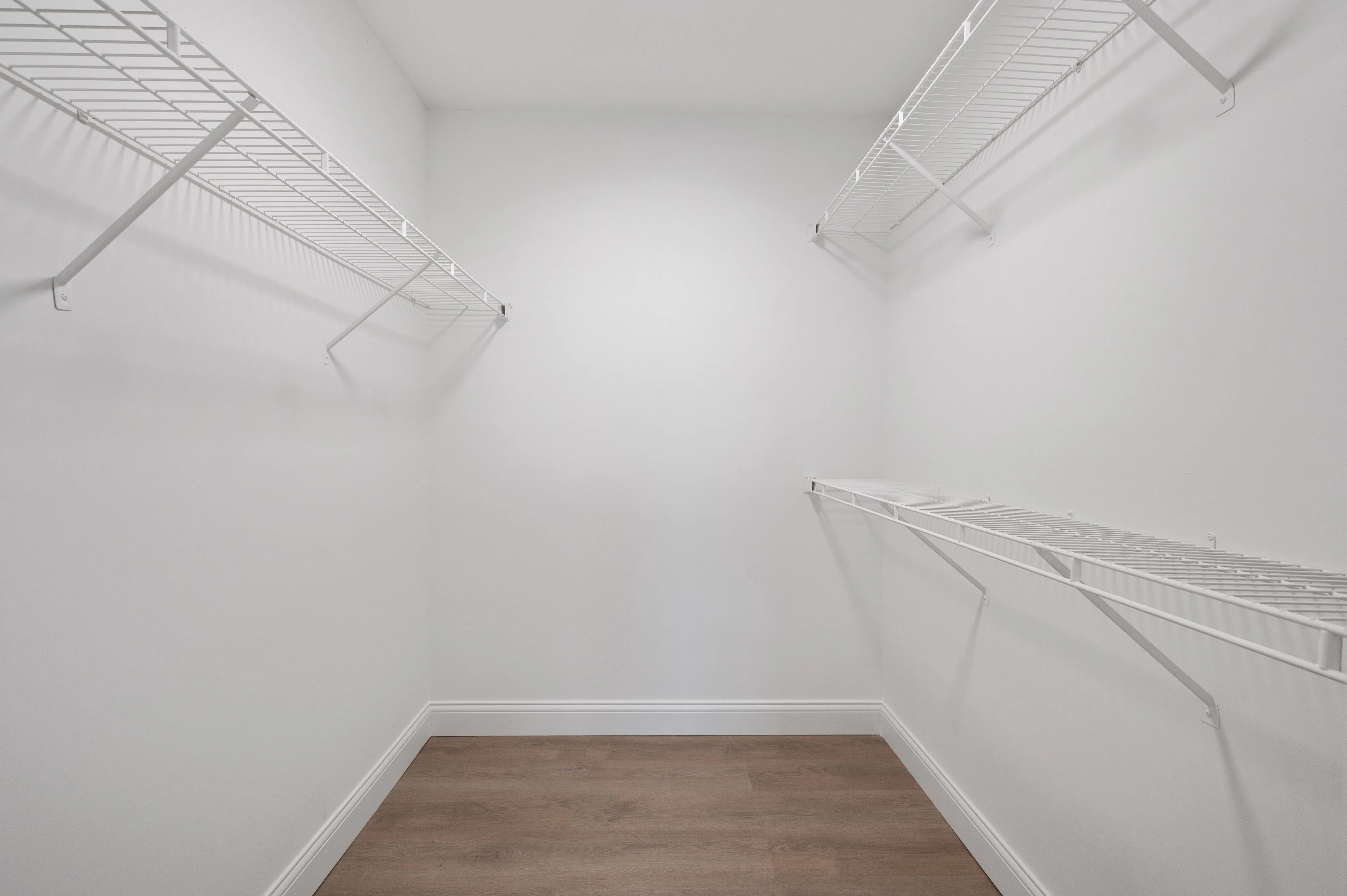 Elegant walk-in closet with ample shelving and hardwood flooring.