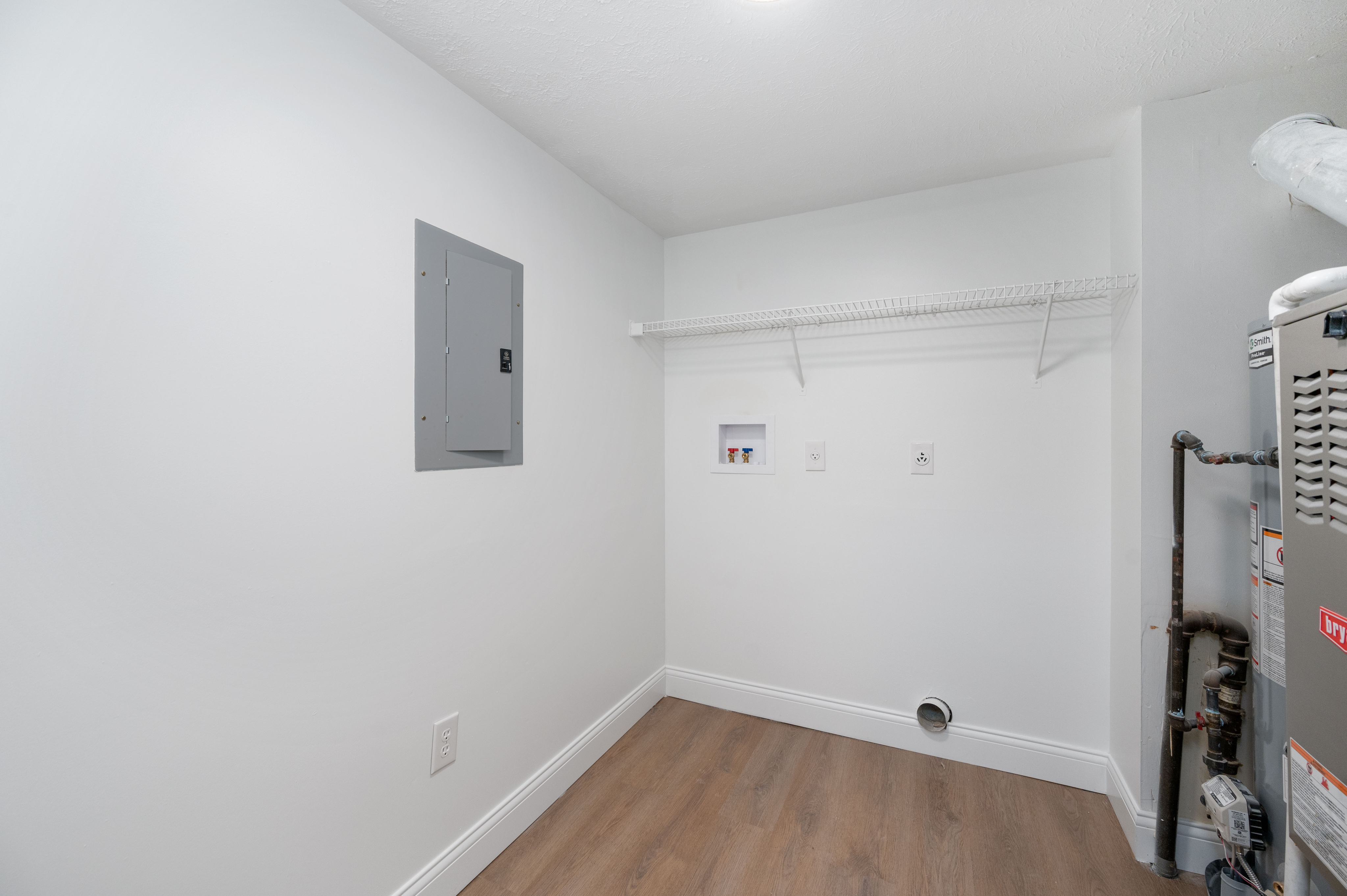 Bright utility room showcasing ample storage with a wall-mounted shelf and modern utility connections.