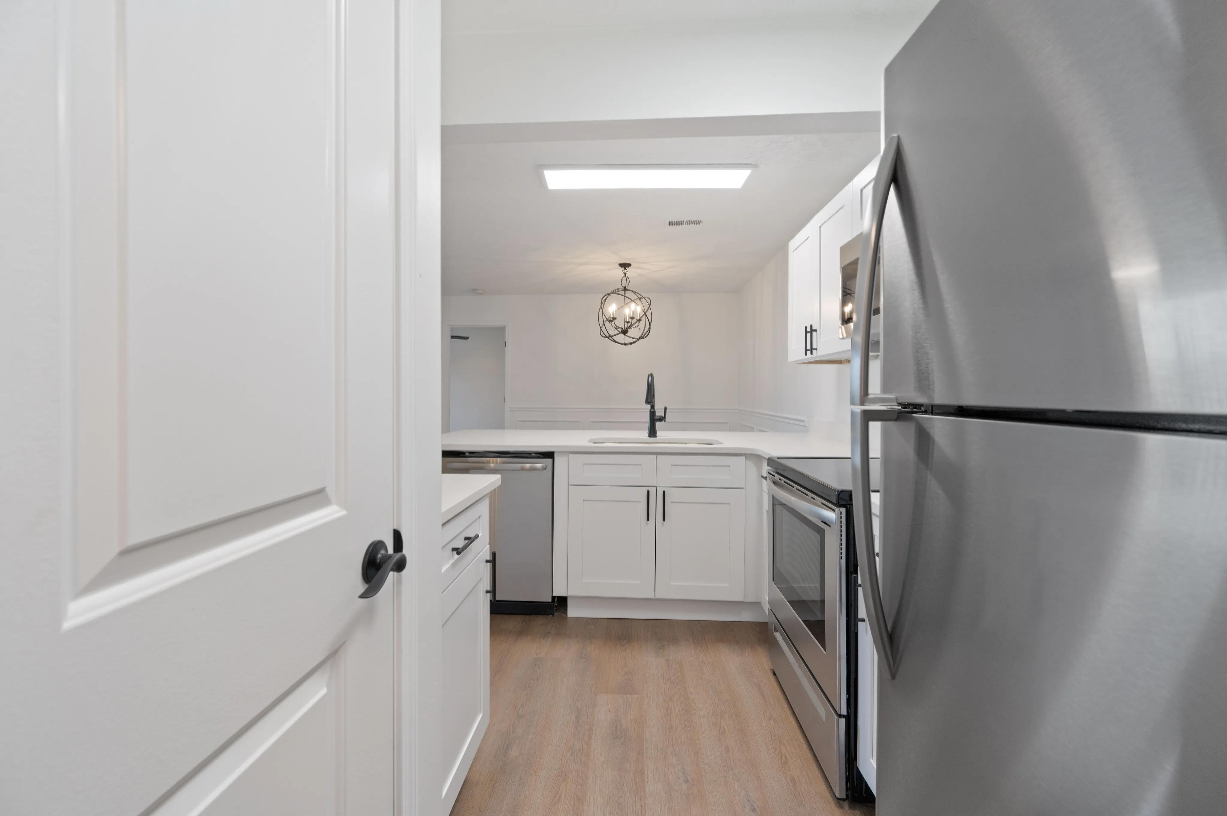Contemporary kitchen with white cabinetry, stainless steel appliances, and a chic pendant light.
