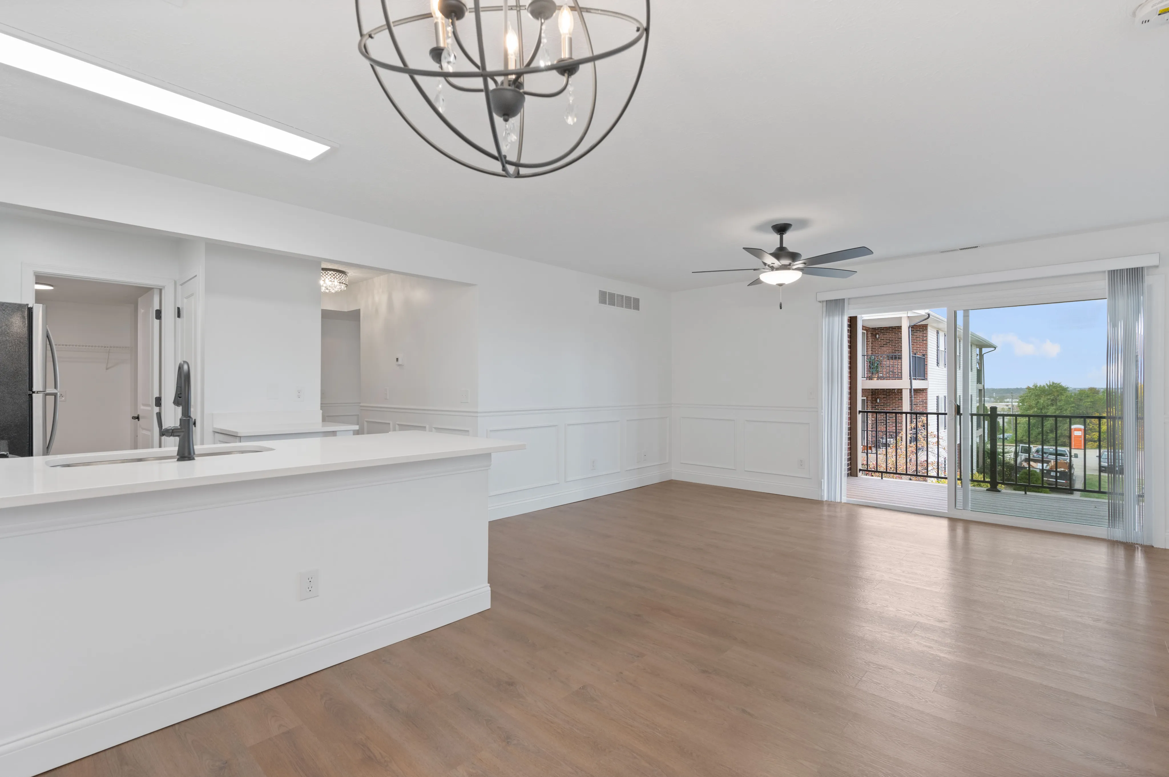Bright open-concept living area with hardwood floors, modern fixtures, and balcony access.
