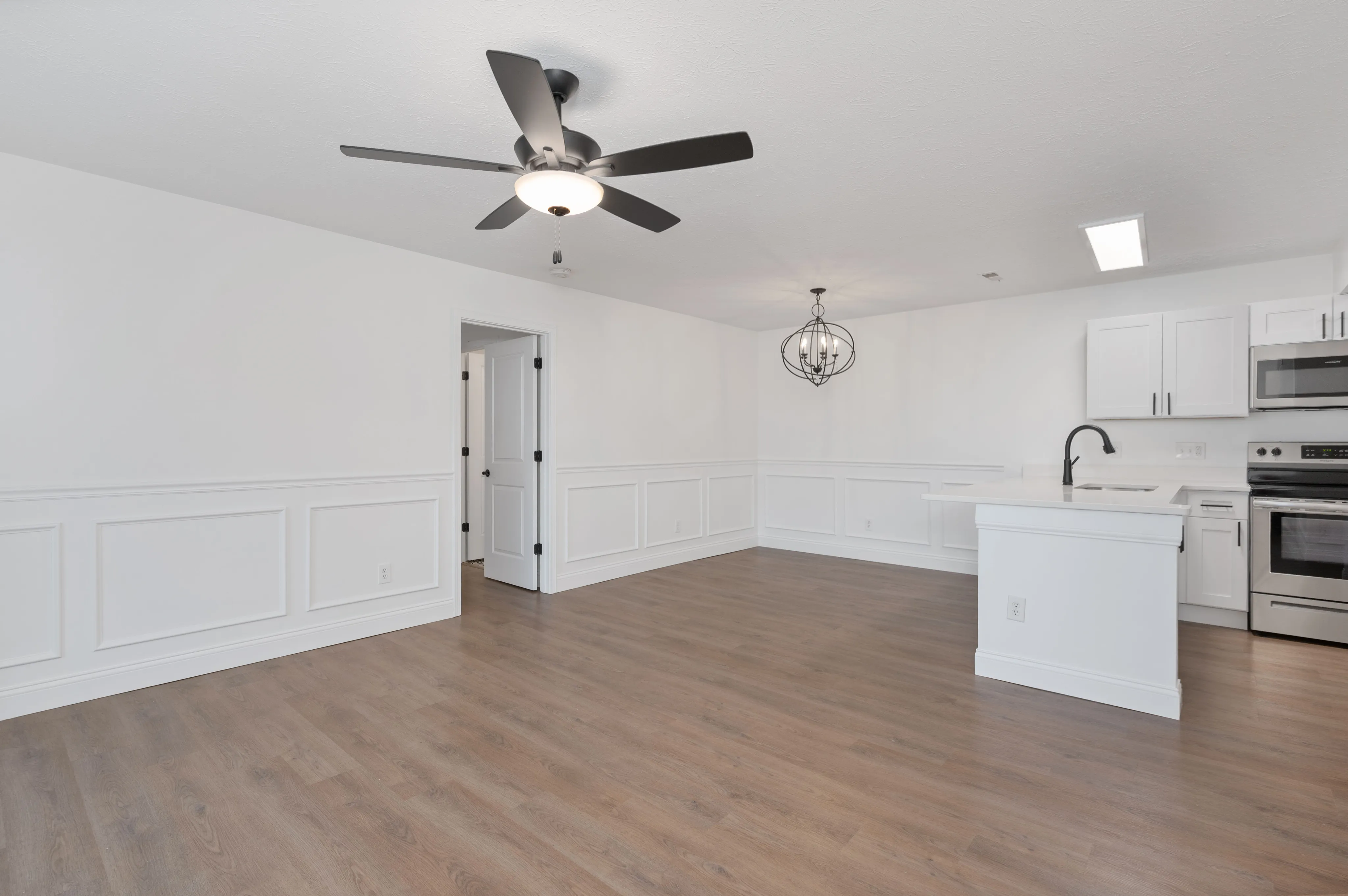 Spacious open-concept room with modern kitchen and elegant chandelier.