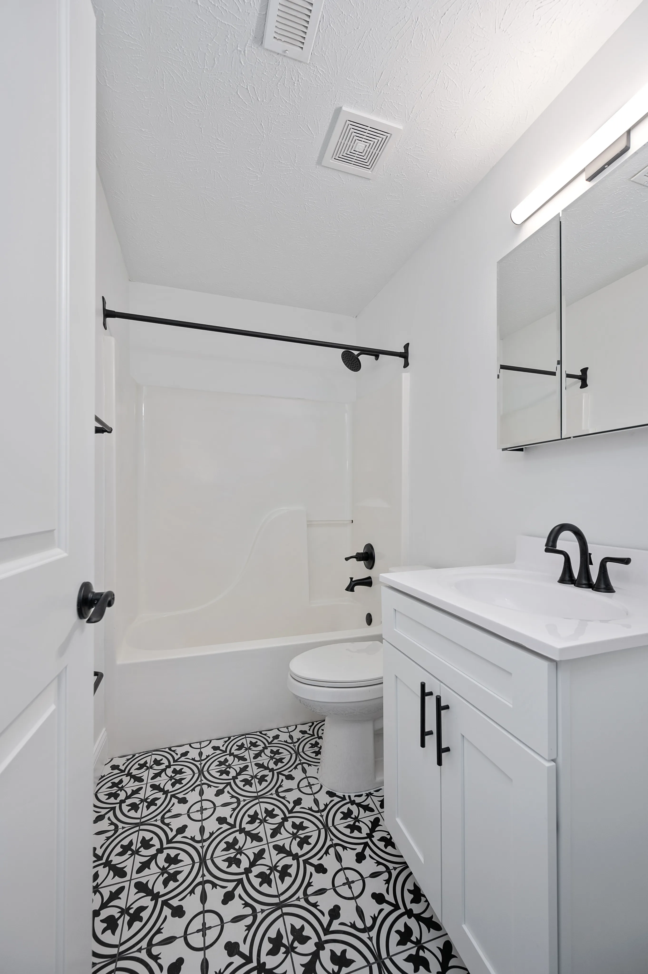 Elegant bathroom with patterned tile flooring, modern white vanity, and sleek fixtures.