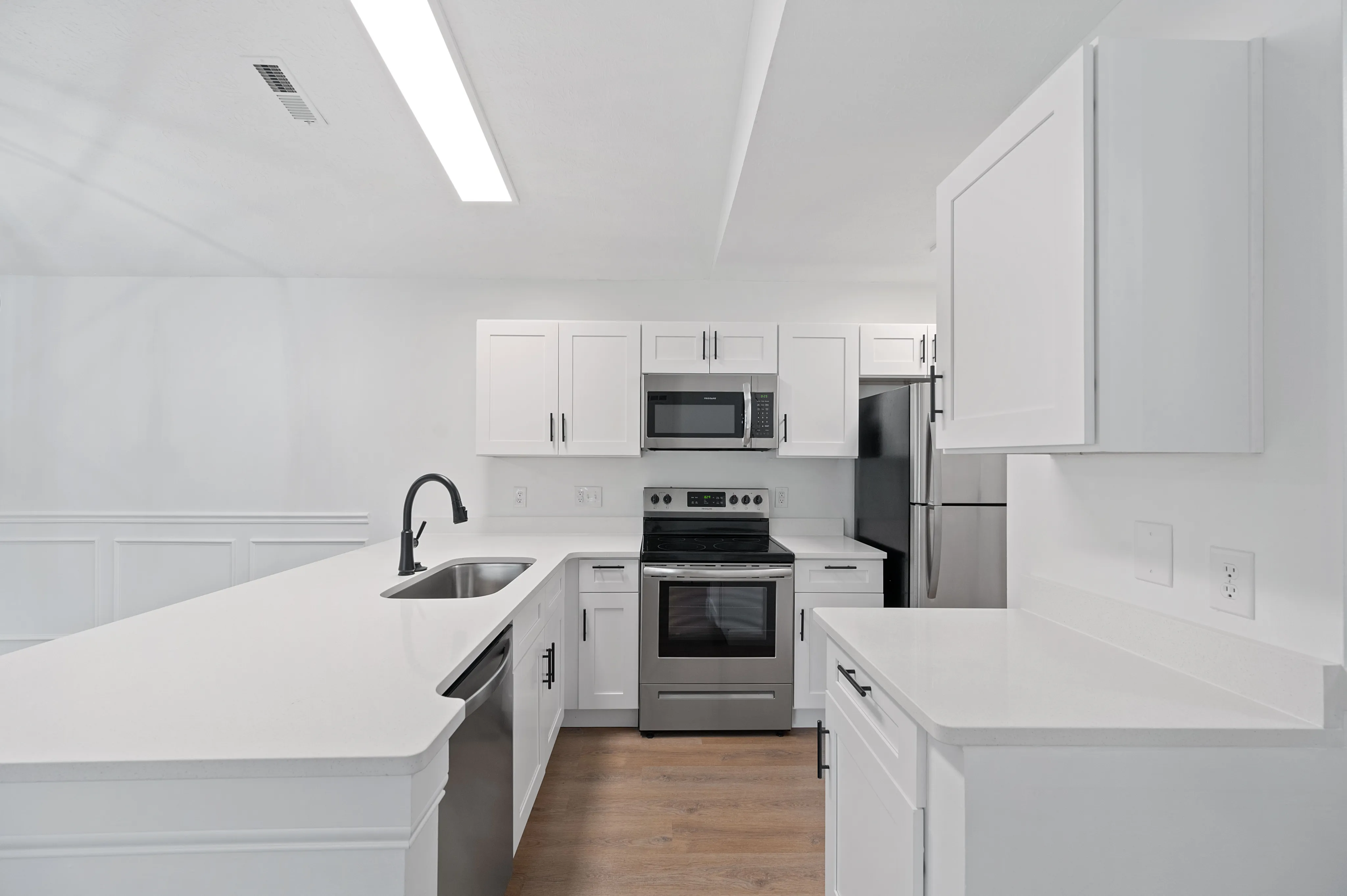 Contemporary kitchen with white cabinetry, stainless steel appliances, and sleek countertops.