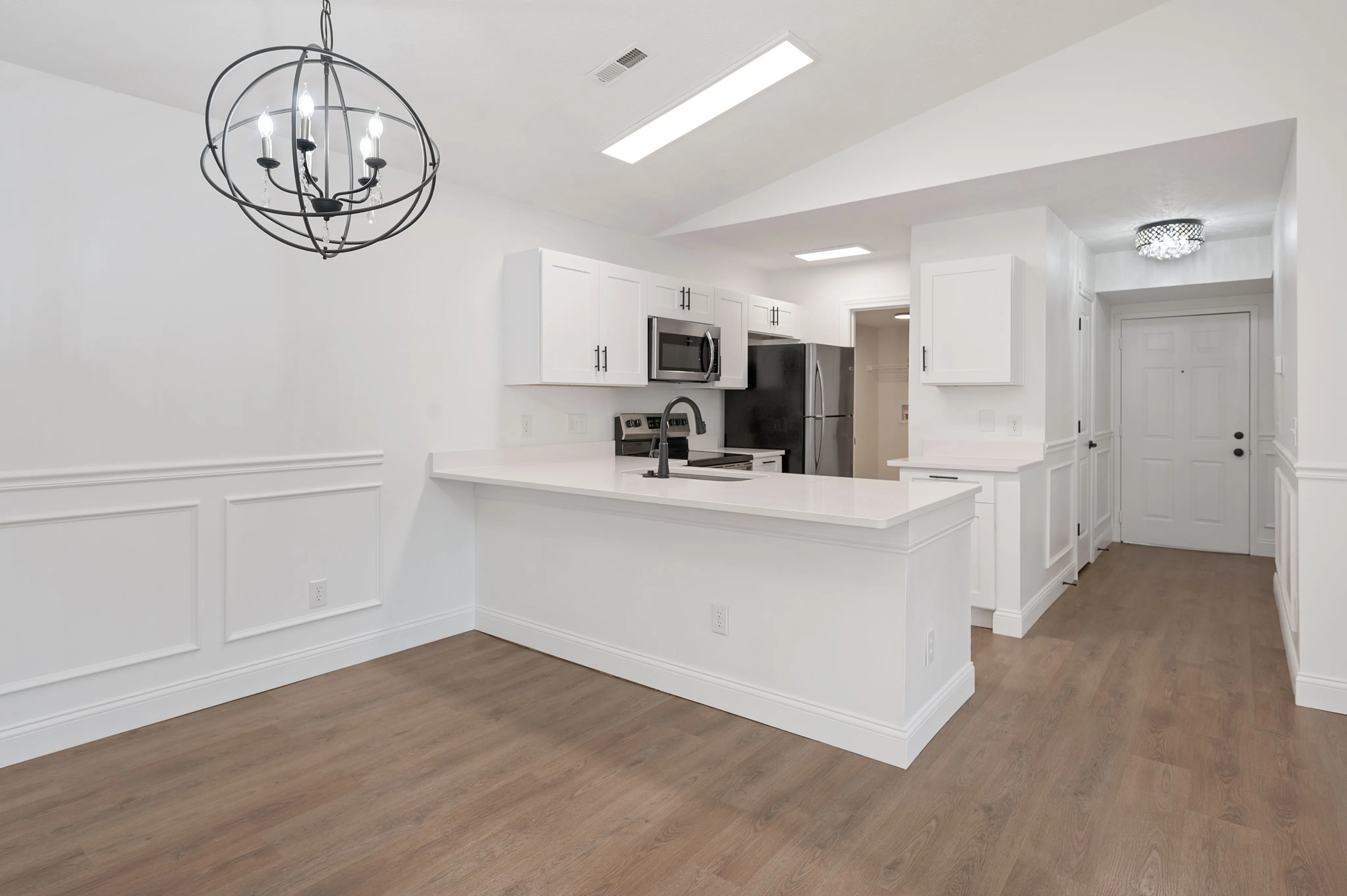 Elegant kitchen with white cabinetry, modern appliances, and an island with a sleek faucet.