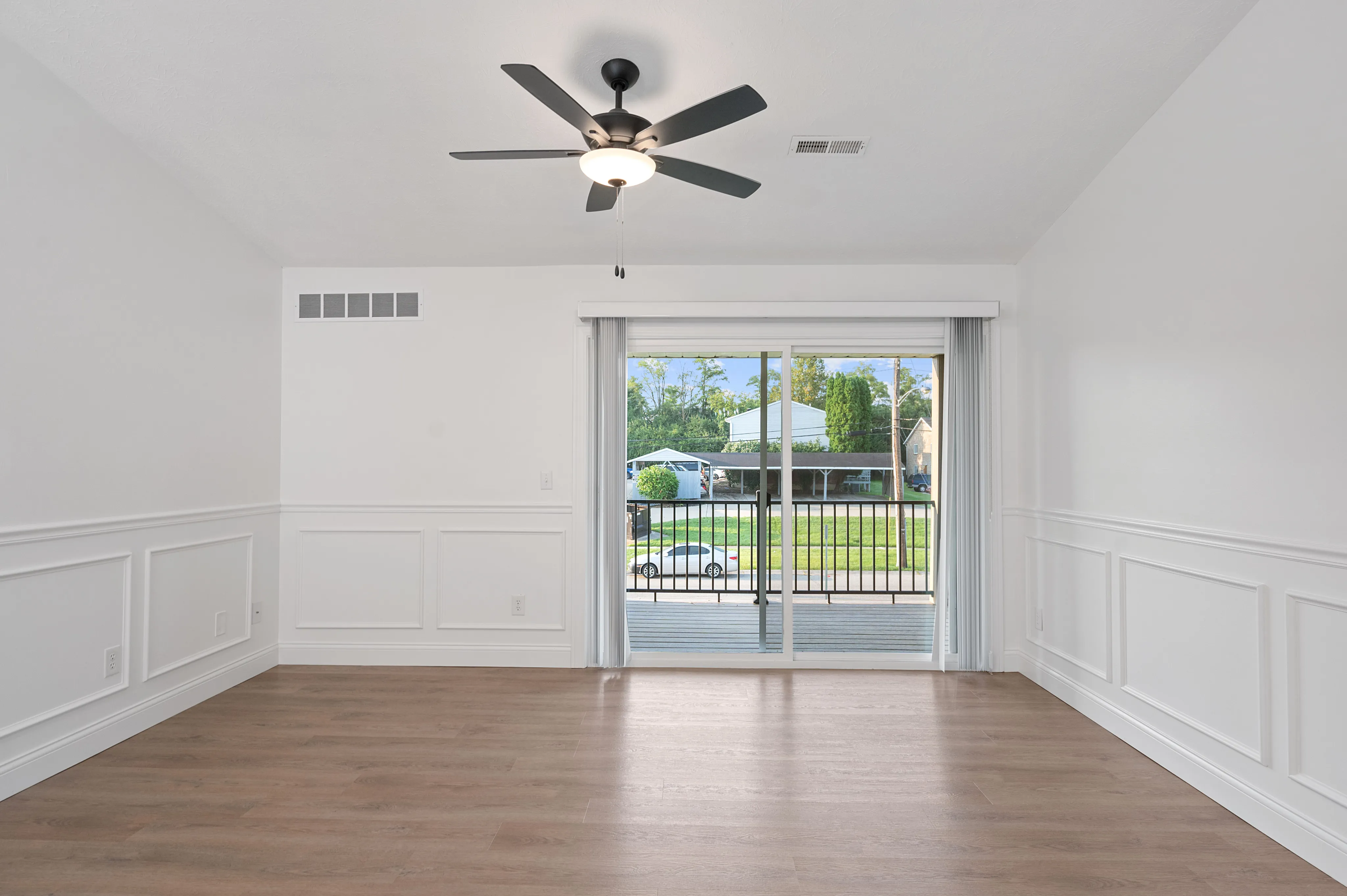 Bright and airy living room with wood flooring and sliding glass doors leading to a balcony.