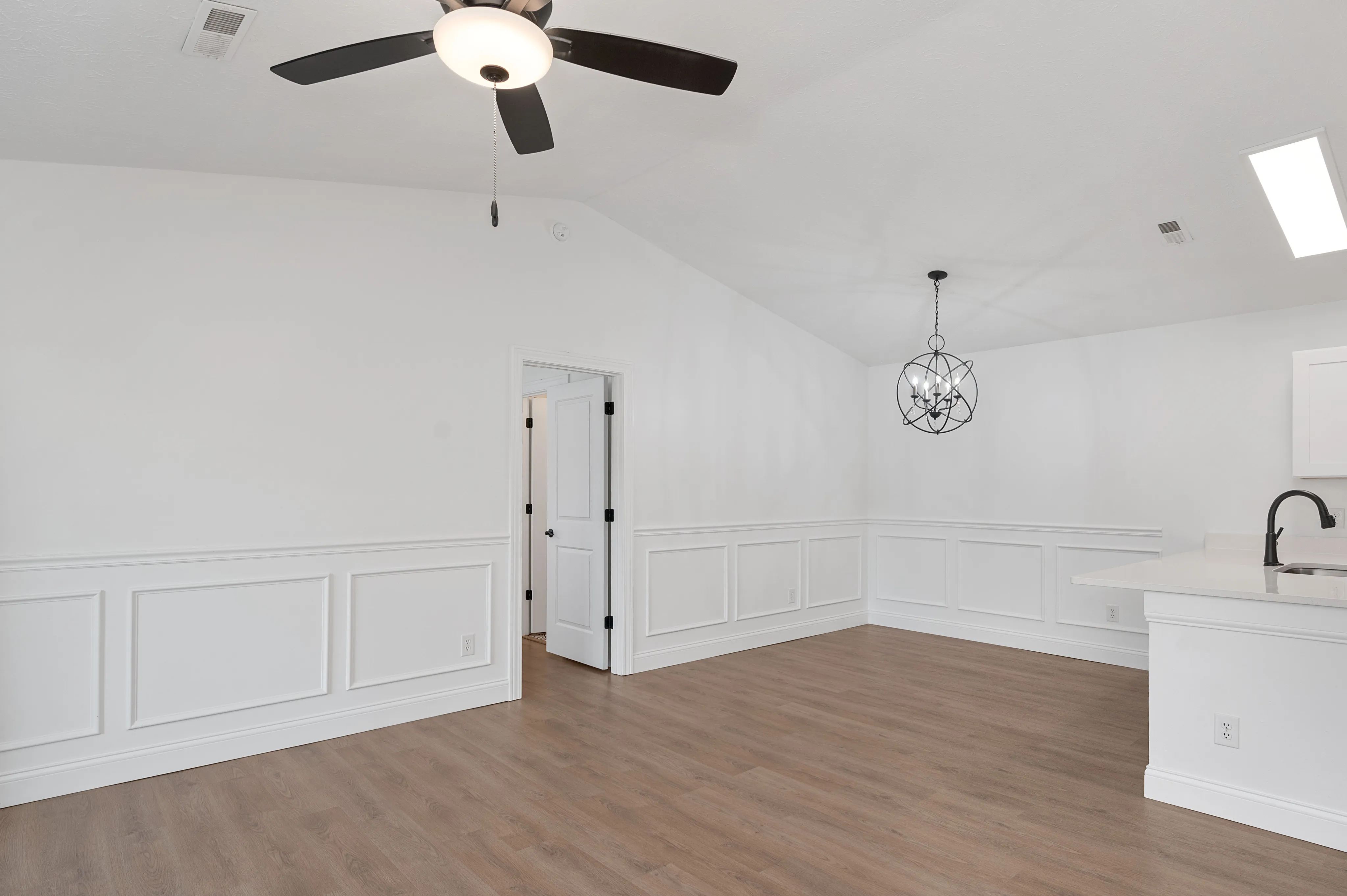 Bright and airy room with white walls, modern lighting, and wooden floors.