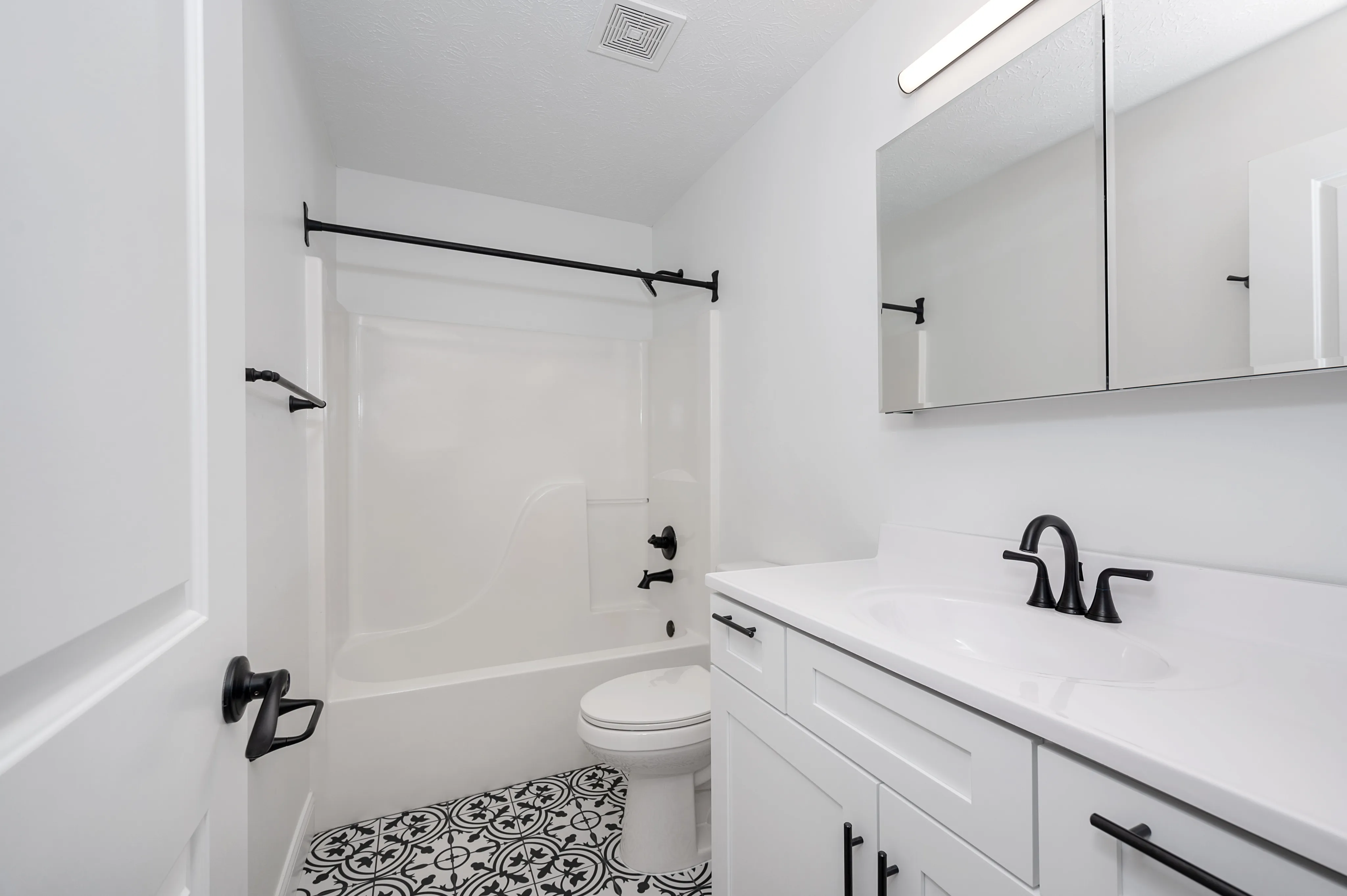 Stylish bathroom featuring a sleek white vanity, modern fixtures, and patterned tile flooring.