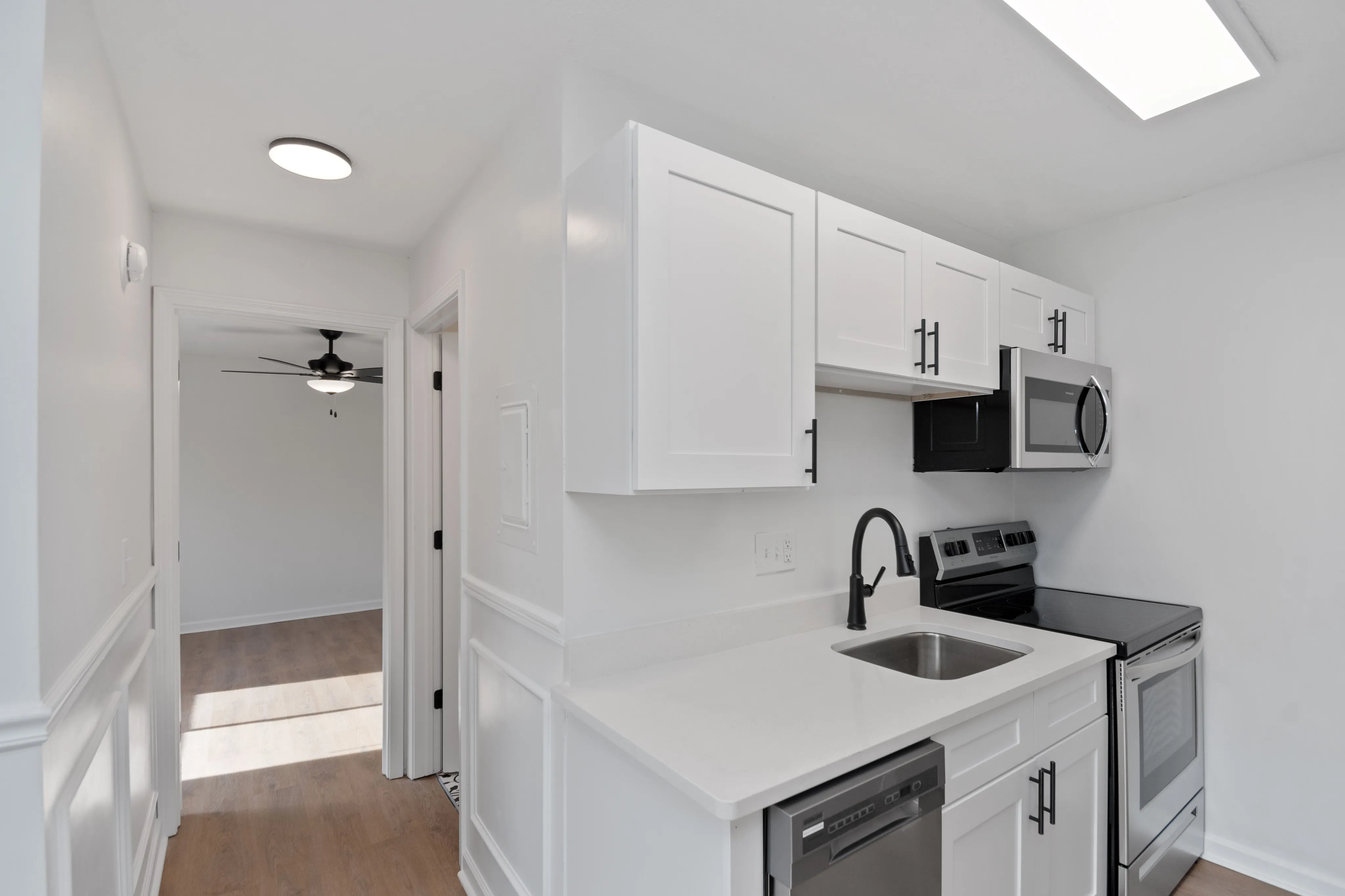 Contemporary kitchen with white cabinetry, stainless steel appliances, and a black faucet.